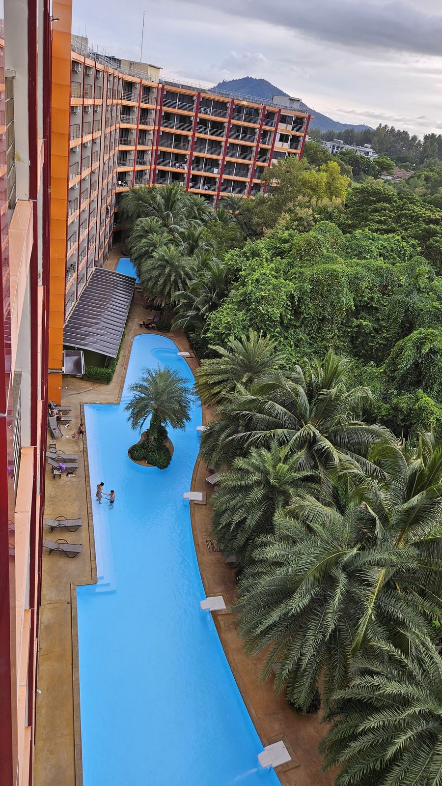Long pool beside a building of Mai Khao Beach Condotel, next to the forest